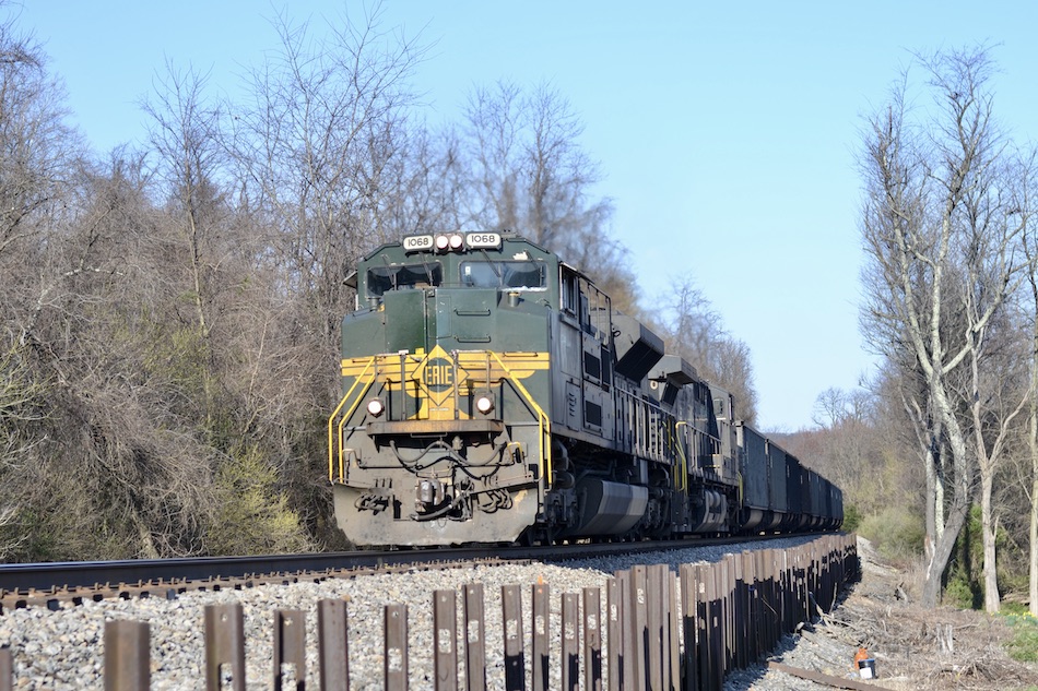 A green and yellow Erie Railroad heritage unit leads a Norfolk Southern loaded coal train through Virginia.