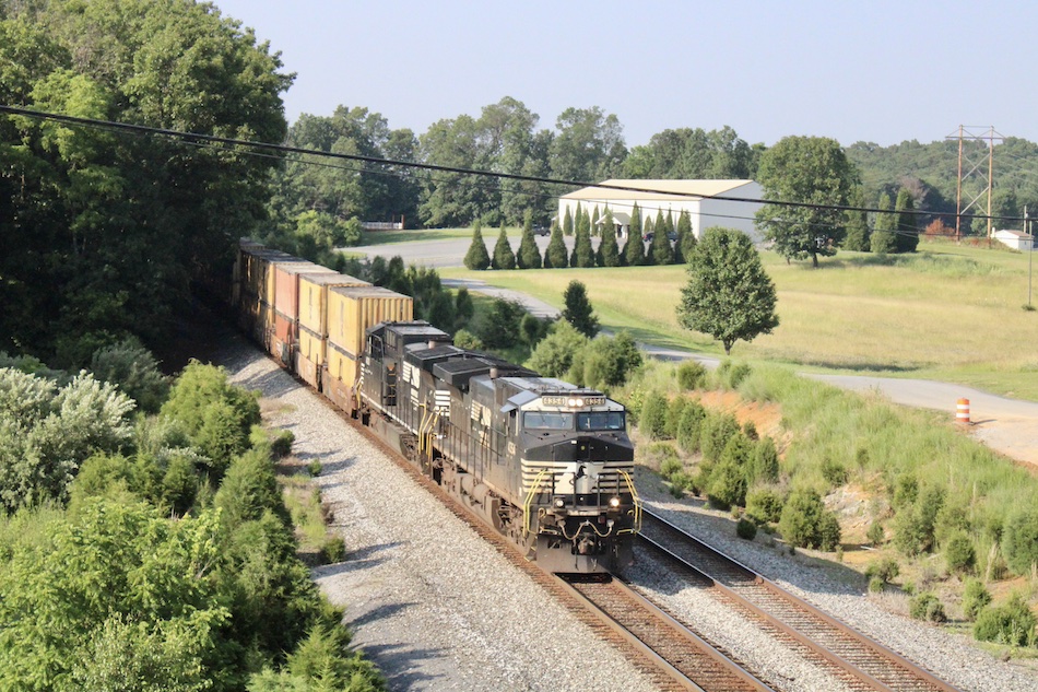 A Norfolk Southern train passing by on a summer day.